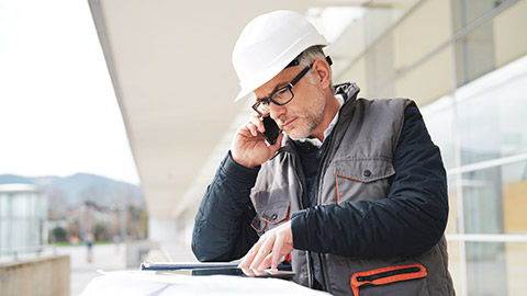 Construction manager on site consulting WHS legislation on a tablet device