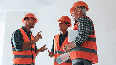 Three workers on a construction site discussing an issue with the job at hand