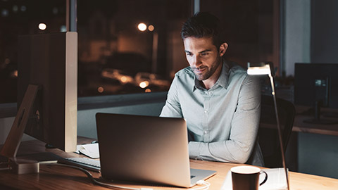 A construction supervisor sitting at desk entering project data into a laptop computer