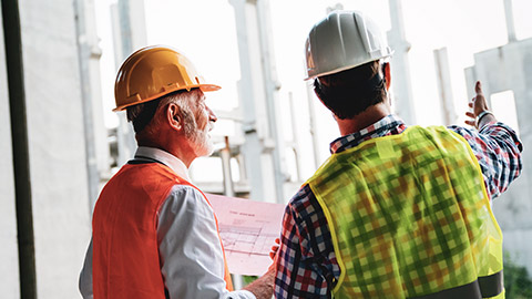 2 construction workers checking a current project for non-compliances