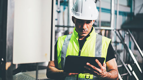 A worker checking compliance of a building and recording on a tablet device