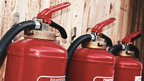 A close view of 3 fire extinguishers hung on a wall