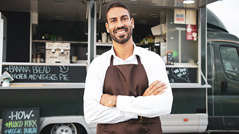 A food truck owner standing in front of his vehicle