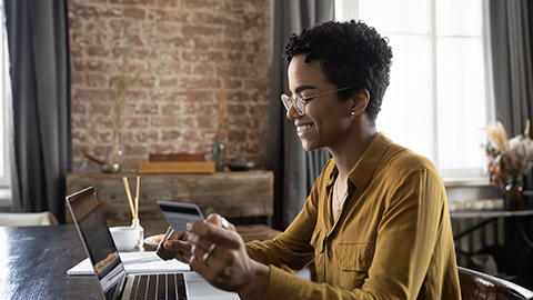 Happy young African customer woman using laptop and credit card for online shopping