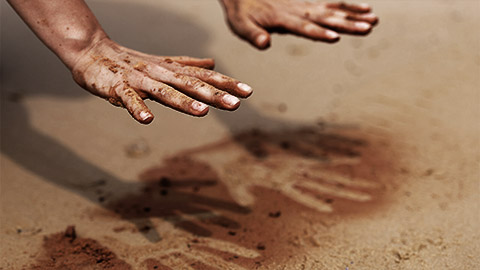 A person marking their hands on the red soil