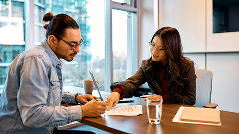 advisor showing her client where to sign a contract during the meeting in the office