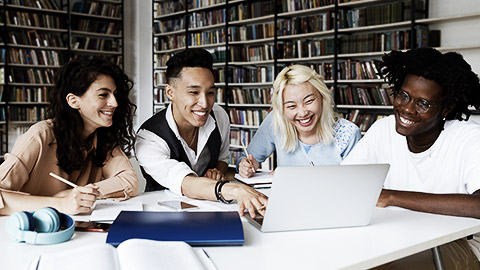 A diverse group of students studying in a library and with a laptop