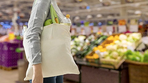 woman with white reusable canvas bag for food shopping over supermarket