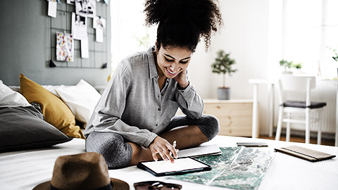 Young woman with tablet and map indoors at home, planning traveling trip.