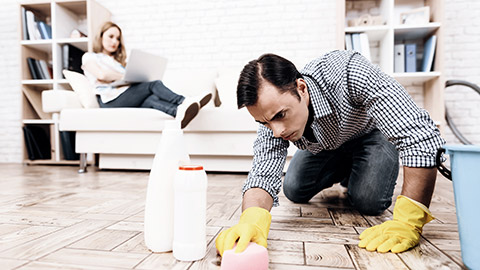 man cleaning while woman sitting on a sofa