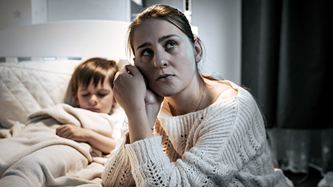 mother sitting next to son on bed