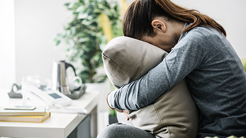 woman burrying head on pillow