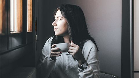 woman sipping coffee infront of the window