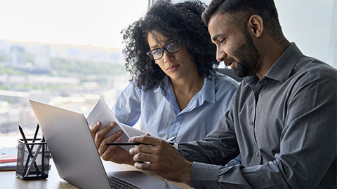 male indian mentor and female African American intern sitting at desk with laptop doing paperwork