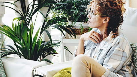 woman casually sitting on sofa, thinking