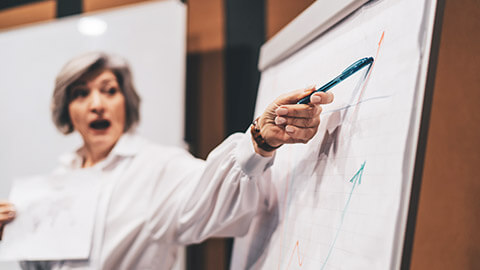 An entrepreneur showing surprise while pointing at a diagram on a flipchart