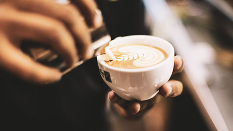 A close view of a barista pouring a coffee