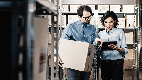 Female Inventory Manager Shows Digital Tablet Information to a Worker Holding Cardboard Box