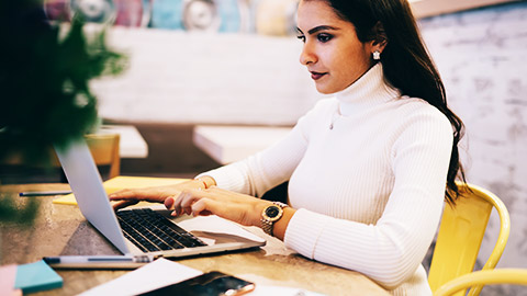 a person typing on laptop while sitting at cafeteria