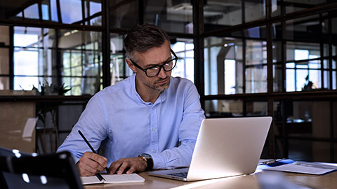 mature man writing on notebook