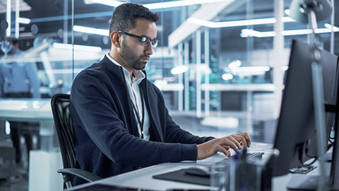 Portrait of a Handsome Hispanic Industrial Engineer Developing 3D Model of a Circuit Motherboard on Computer CAD Software in a Factory. Modern Technological Research and Development Center.