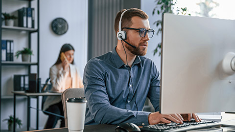 Man is using computer. Two employees are working together in the modern office.