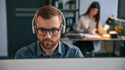 Portrait of man. Woman is on background. Two employees are working together in the modern office.