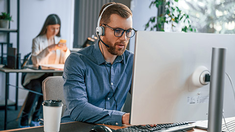 Man is using computer. Two employees are working together in the modern office.