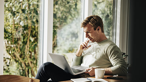 Man thinking with computer and notes