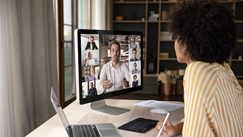 Focused young African American female employee involved in video call distant meeting with team leader and colleagues, discussing online project distantly,