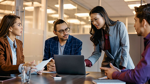 Asian female executive and her business team cooperating while working on a computer during the meeting.