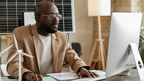 Designer in eyeglasses sitting at his workplace and typing on computer, he working with design project at office