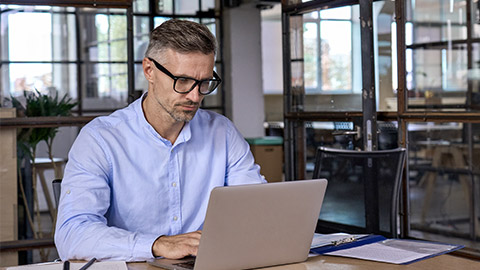 Focused busy mature business man lawyer ceo trader using computer, typing, working in modern office