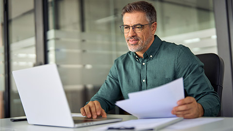 mature male hr manager holding documents using laptop