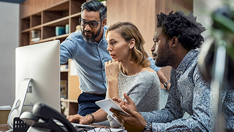 Focused businesspeople discussing project while looking at computer screen.