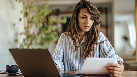 Concentrated young woman, copying a document onto the laptop