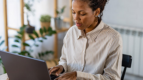 Young African Ethnicity Freelancer Woman Working On Laptop At Home Office And Taking Notes