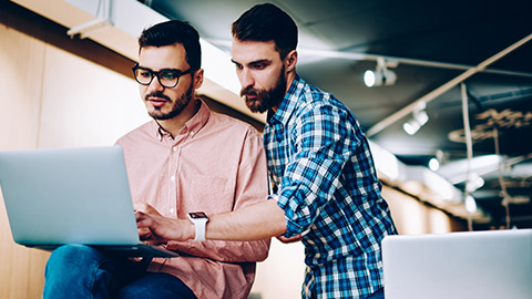 2 designers discussing a project on a laptop