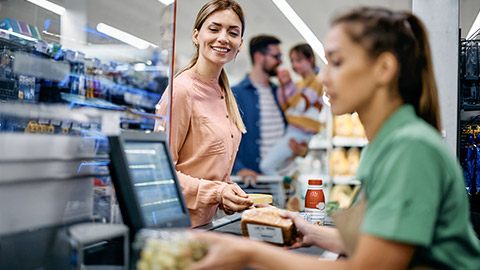 Happy woman paying for groceries at checkout while buying with her family in supermarket