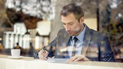 Businessman sitting in coffee shop, signing contract