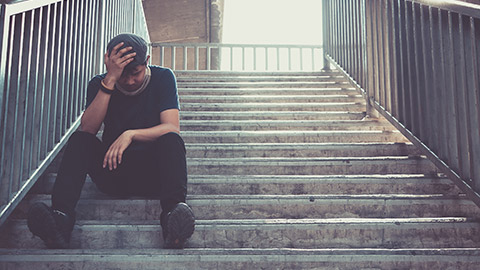 A sd person sitting alone on steps