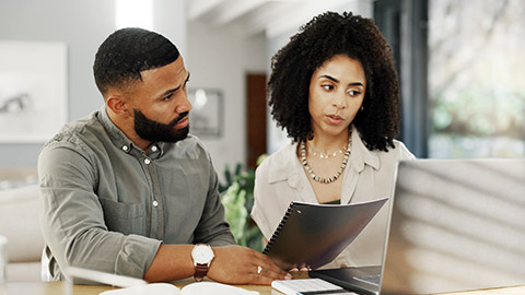 Couple on discussion on paper over a computer