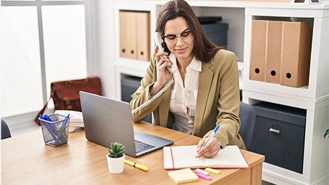 business worker talking on telephone writing on notebook at office