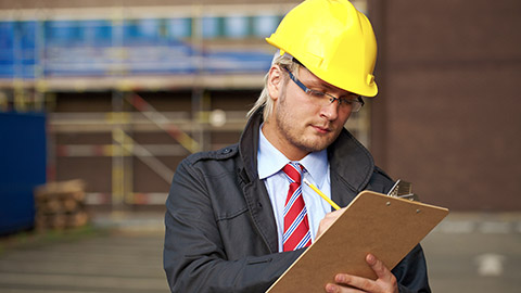 young architect or inspector make some notes, office building as blurred background