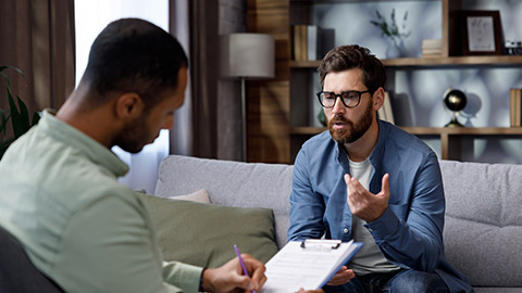 A man sits on a couch and talks to a psychotherapist