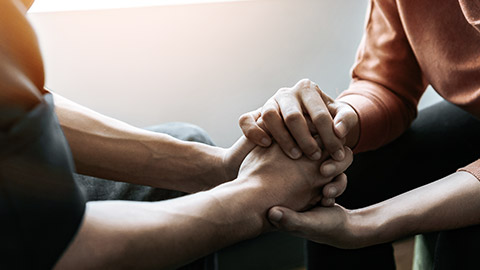 Two persons holding hands for support