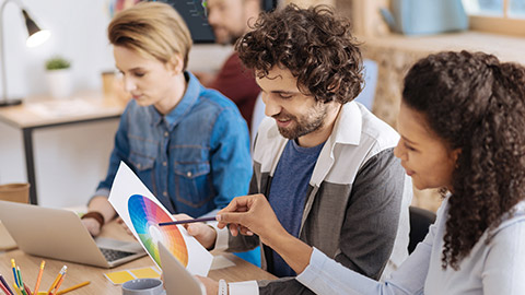 man smiling and looking at a sheet of paper while sitting at the table with his colleagues