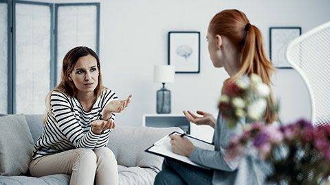 a woman talking to her patient sitting on the couch in therapist office