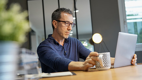 guy having hot drink, working on laptop