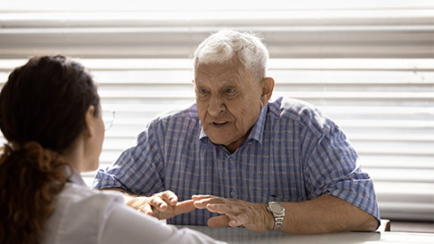 Old man retiree sit by desk in examination room complain on bad health